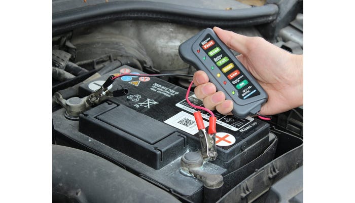 Hand holding battery tester over battery