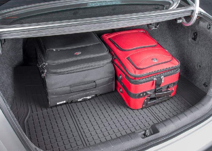 A rubber trunk mat in an open car trunk with two suitcases.