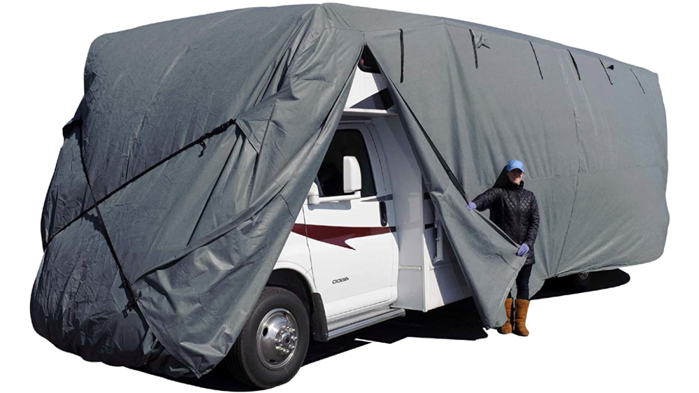 RV cover covering RV. Woman standing holding the corner of an unzipped panel