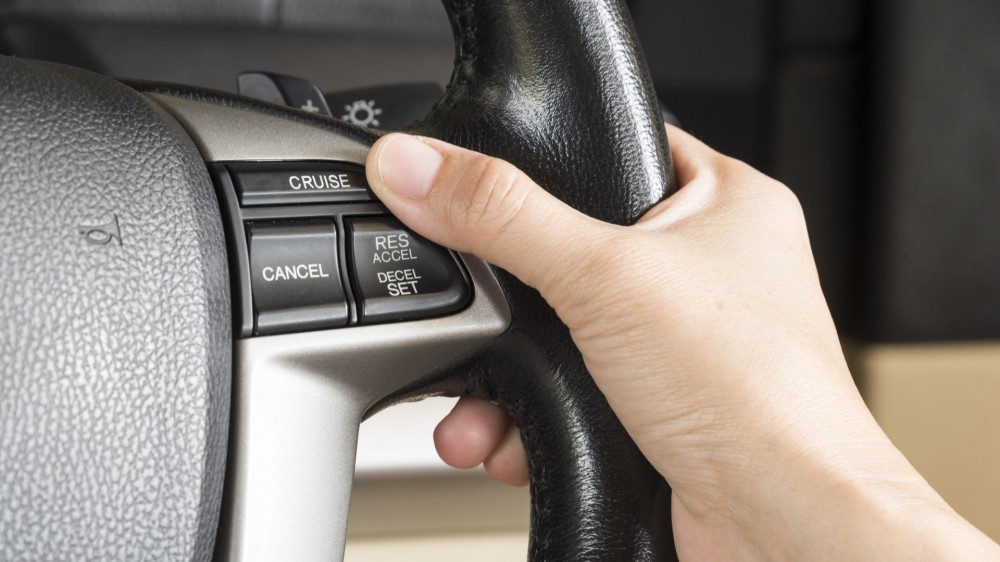 A person activates a cruise control in a car.