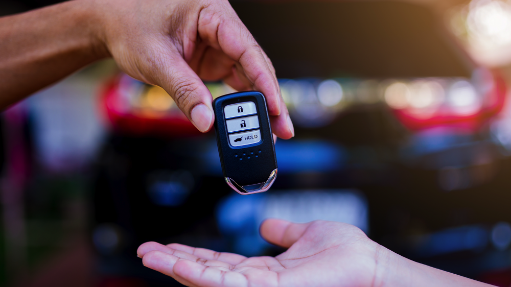 Someone handing a key fob to another person.